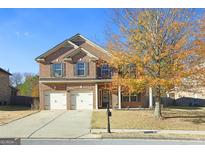 Traditional two-story brick home featuring a two-car garage and well-manicured front lawn at 960 Spanish Moss Trl, Loganville, GA 30052