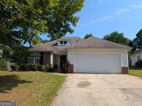 Charming single-story home with a well-maintained lawn, two-car garage, and partial brick facade at 6195 Winston Trce, Mcdonough, GA 30252