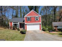 Charming two-story home with red siding, black shutters, and a well-manicured lawn at 7472 Woods Ct, Lithonia, GA 30058