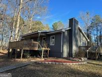Charming home with a wooden deck and a landscaped yard surrounded by mature trees at 2020 Moore Rd, Moreland, GA 30259