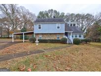 Charming two-story home with stone accents, a carport, and mature trees in a landscaped yard at 3954 Swathmore Ln, Duluth, GA 30096