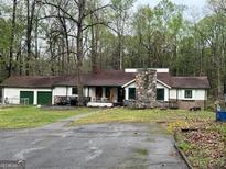 Ranch home featuring brick fireplace, two-car garage, and mature trees at 2497 Old Jackson Rd, Locust Grove, GA 30248