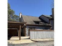 Two-story home featuring aged siding, a carport, and a low fence at 97 Willowick Dr, Lithonia, GA 30038