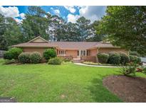 Brick ranch house with a spacious lawn and mature trees at 215 Creekside Trl, Fayetteville, GA 30214