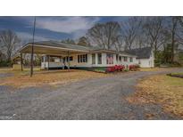 Charming home with a covered carport, white siding, and a well-maintained gravel driveway at 12178 Brown Bridge Rd, Covington, GA 30016