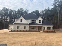 Charming two-story home with stone and white siding, a manicured lawn, and a three car garage at 8795 St Patrick'S Way # 2, Winston, GA 30187