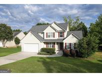 Two-story house with a white garage door and landscaped lawn at 327 Oakland Bay Ct, Loganville, GA 30052