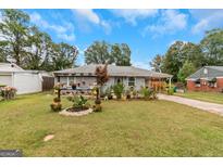 Ranch home with gray brick exterior, landscaped yard, and a covered patio at 5346 Lee Cir, Forest Park, GA 30297