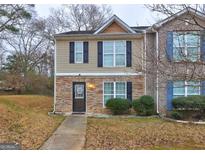 Two-story townhome with stone and vinyl siding, featuring a walkway and landscaping at 8424 Carlington Ln, Jonesboro, GA 30236
