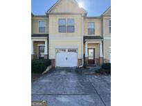 Tan two-story townhome with white garage door and landscaping at 6022 Centennial Run, Atlanta, GA 30349