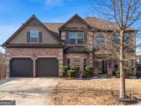 Brick two-story house with a three-car garage and landscaping at 704 Kitts Ct, Mcdonough, GA 30253