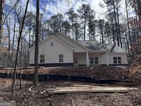 Exterior view of home with gray siding, black foundation, and tree backdrop at 5525 Belle Meade Dr, Villa Rica, GA 30180