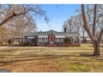 Gray house with brick accents, covered porch, and large yard at 60 N East Main St, Hampton, GA 30228