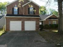 Brick two-story house with a three-car garage and a well-maintained lawn at 4408 Idlewood Park, Lithonia, GA 30038