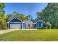 Charming blue home featuring a spacious lawn, attached two-car garage, and bright white painted brick accents at 2037 Emily Dr, Social Circle, GA 30025