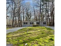 Charming single-story home with a covered front porch, surrounded by a lush, wooded landscape at 58 Pinewood Dr, Carrollton, GA 30116