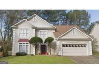 Two-story house with a tan exterior, red door, and a two-car garage at 635 Watson Bay, Stone Mountain, GA 30087