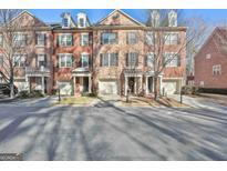 Brick townhouses with attached garages and landscaping at 32 American Walk, Peachtree City, GA 30269