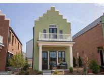 Two-story green house with balcony, front porch, and landscaping at 165 Kelmscott Ln., Fayetteville, GA 30214