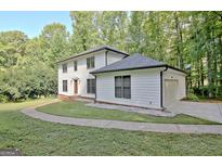 Charming two-story home with attached garage, lush lawn, and mature trees at 215 Kingswood Dr, Fayetteville, GA 30215