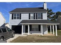 Two-story house with gray siding, a covered porch, and a attached garage at 9418 Sleepy Hollow Ln, Jonesboro, GA 30238