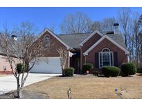 Charming brick home with a manicured lawn, attached garage, and mature trees on a sunny day at 213 Meridian Dr, Stockbridge, GA 30281