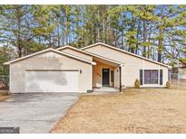 Charming single-story home with a well-maintained lawn and attached two-car garage at 210 Imad Ct, Fairburn, GA 30213