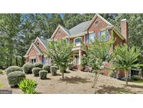 Beautiful brick home with blue shutters and a lush, landscaped front yard with mature trees at 230 Hedgewick Way, Tyrone, GA 30290