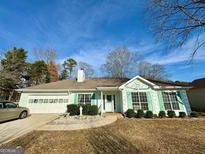 Ranch style home with light green exterior, attached garage, and landscaping at 110 Somerset Dr, Covington, GA 30016