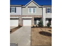 Charming townhome with gray siding, brick accents, a one-car garage, and well-maintained landscaping at 137 Swindon Dr, Mcdonough, GA 30253