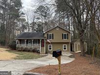 Charming home featuring a covered front porch, American flag, and cozy curb appeal at 3025 Sumit Wood Nw Dr, Kennesaw, GA 30152