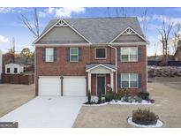 Two-story brick home with a three-car garage and landscaping at 3573 Stonebranch Ln, Loganville, GA 30052