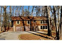 Exterior view of a home featuring a two-car garage and wooded surroundings at 2395 River Run Dr, Douglasville, GA 30135