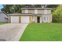 Two-story house with a two-car garage and well-manicured lawn at 3880 Springleaf Ct, Stone Mountain, GA 30083