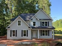 Two-story home featuring black shutters and grey siding nestled in a wooded neighborhood on a sunny day at 142 Asa Moseley Rd, Mcdonough, GA 30252