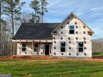 View of the new home's facade, currently under construction, with visible windows and roof against a green lawn at 136 Asa Moseley Rd, Mcdonough, GA 30252