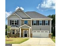 Charming two-story home with a manicured lawn, stone accents, and a two-car garage at 13232 Tolstoy Drive, Covington, GA 30014