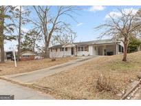 White brick ranch home with long driveway and covered carport, showcasing a quaint suburban setting at 1066 Cleavemark Dr, Clarkston, GA 30021