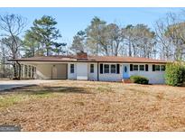 White brick ranch house with light blue door, attached carport, and spacious yard at 215 Elliott Rd, Mcdonough, GA 30252