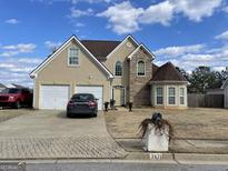 Two-story house with a two-car garage and a landscaped yard at 7471 Ledgestone Ln, Riverdale, GA 30274