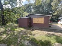 Red house exterior with boarded windows and a small shed at 519 Rock Quarry Rd, Austell, GA 30106