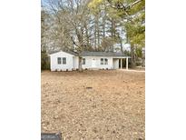 Charming single-story home with a front yard featuring mature trees and a welcoming covered porch at 663 Airport Rd, Oxford, GA 30054