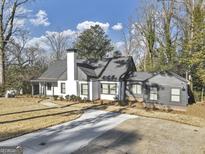Charming home with a well-manicured lawn, long driveway, and inviting curb appeal on a sunny day at 1571 Boulevard Lorraine Sw, Atlanta, GA 30311