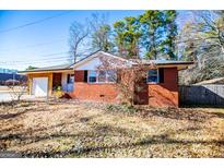 Brick ranch house with attached garage and mature trees at 653 Temple St, Lithia Springs, GA 30122