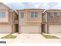 Two-story townhome with attached garage and neutral color brick exterior at 4121 Fulson Dr, Lilburn, GA 30047