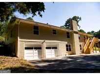 Two-story home featuring an attached garage and a brick chimney at 2751 Colonial Dr, College Park, GA 30337