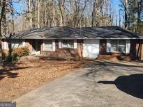 Brick ranch home with attached garage and mature trees at 8587 Cumming Hwy, Canton, GA 30115