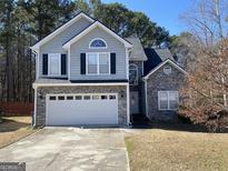 Two-story house with gray siding, stone accents, and a two-car garage at 2905 Splitwood Dr, Snellville, GA 30078