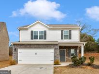 Two-story home featuring stone accents, a two-car garage, and a well-manicured lawn at 144 Oliver Dr, Locust Grove, GA 30248