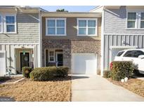 Two-story townhome with brick and siding exterior, attached garage, and landscaping at 2391 Camden Oak Way, Lithonia, GA 30058